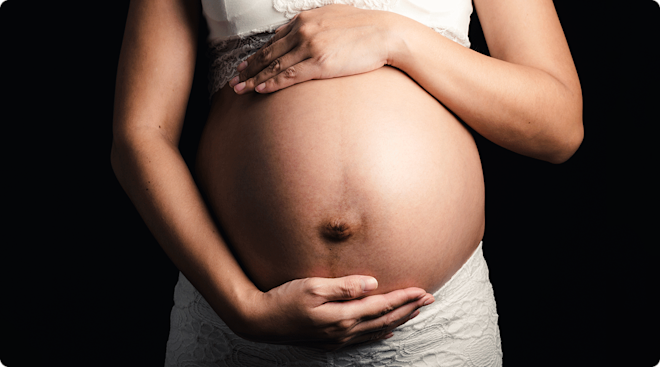 pregnant woman holding belly with dark background