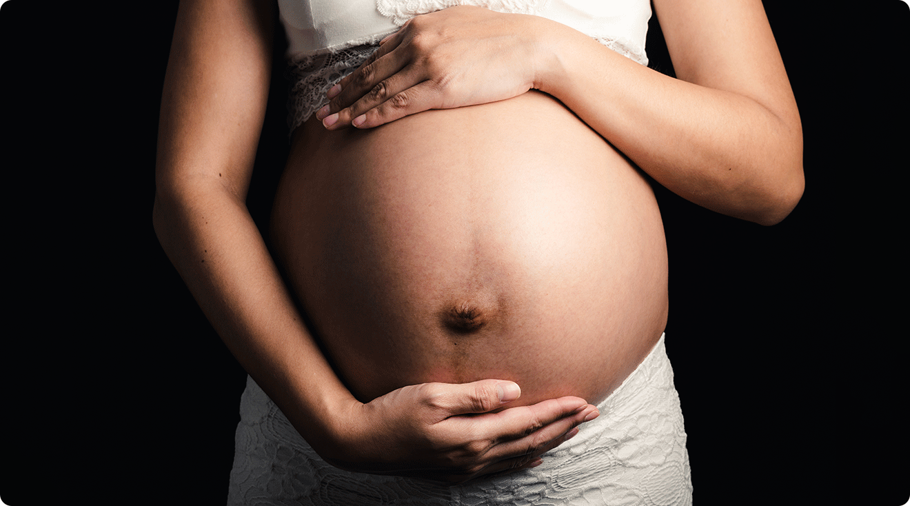 pregnant woman holding belly with dark background