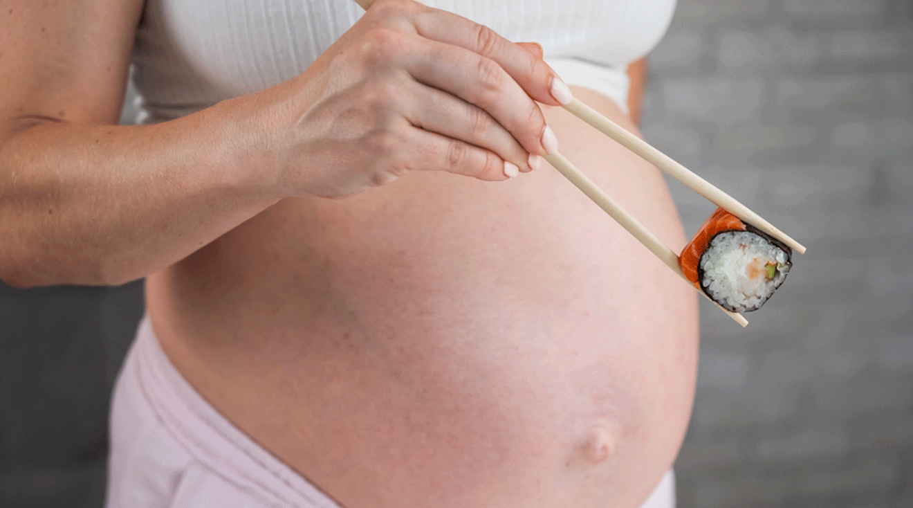 pregnant woman holding sushi in chopsticks 