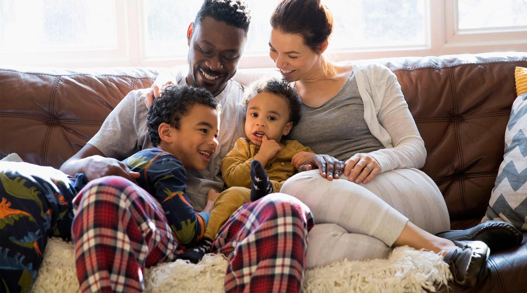 family cuddling on couch together at home