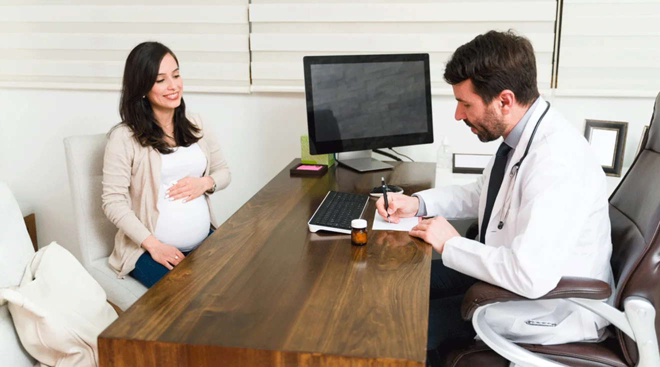 pregnant woman talking to OBGYN at desk in office