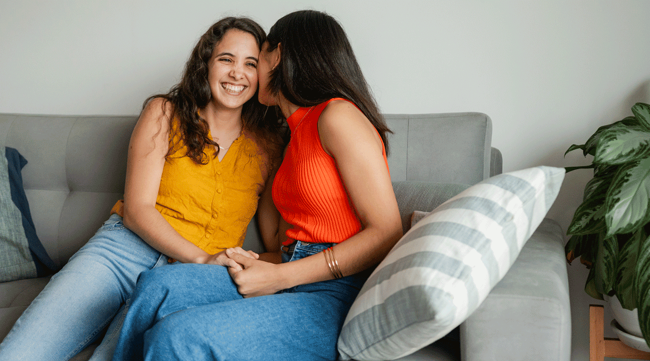 happy lesbian couple sitting on couch at home