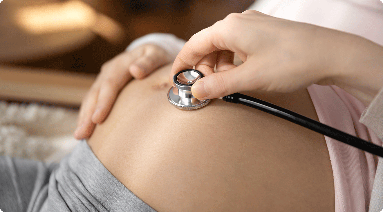 doctor using stethoscope on pregnant belly to hear fetal heartbeat