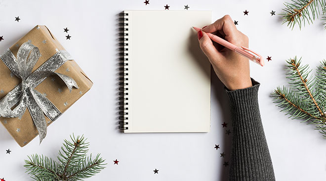 person's hand about to start writing holiday shopping list