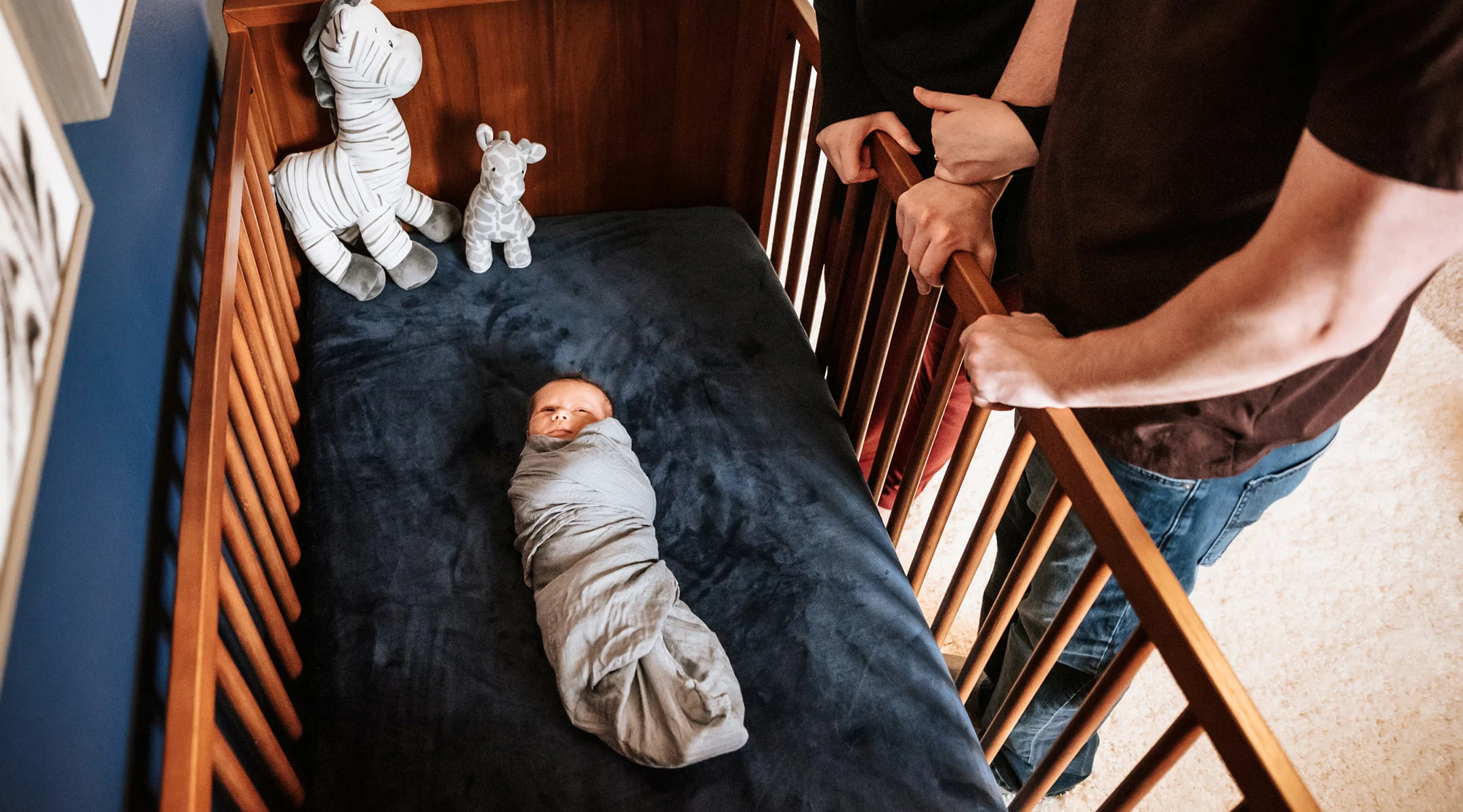 new parents looking at their newborn in its crib