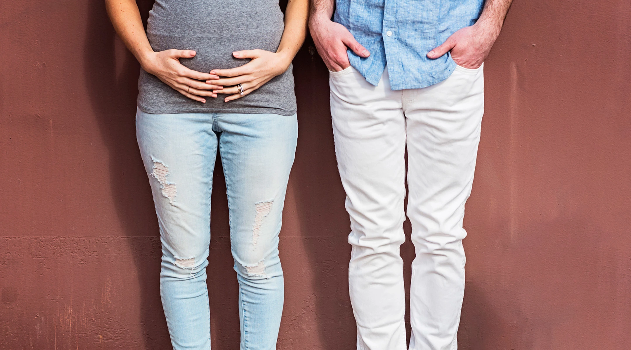 pregnant woman with her hands on belly standing next to her partner