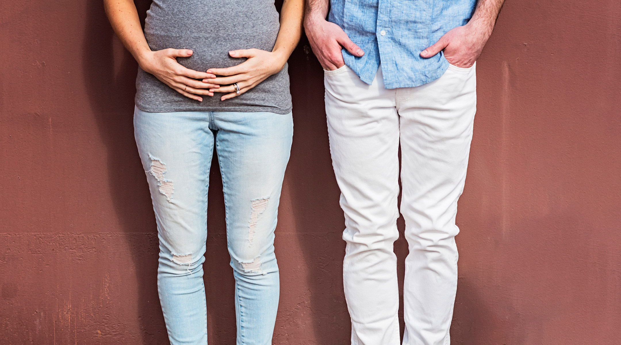 pregnant woman with her hands on belly standing next to her partner