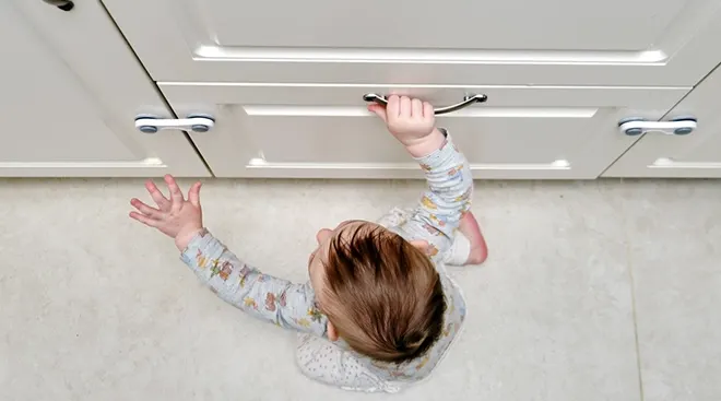 baby climbing on cabinets in home