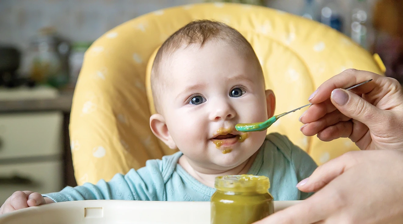 baby being fed baby food while sitting in high chair