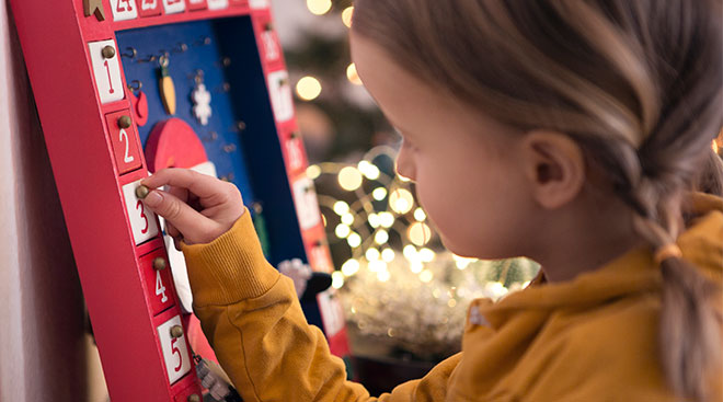 Little girl plays with advent calendar during the holiday season. 