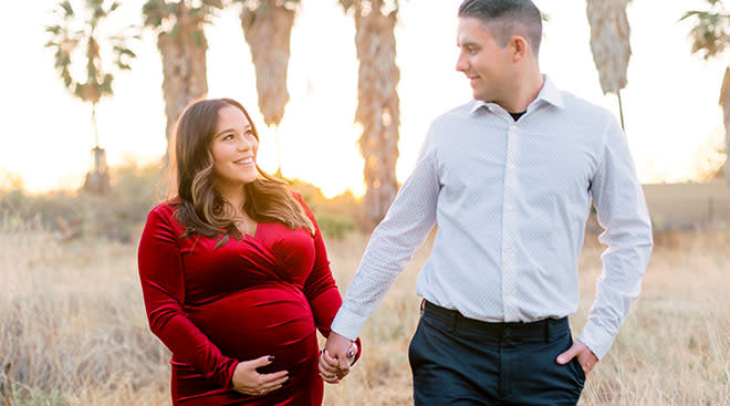 Pregnant woman touching her belly and walking outside with her partner. 