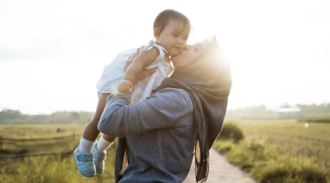 mother holding and kissing baby outside