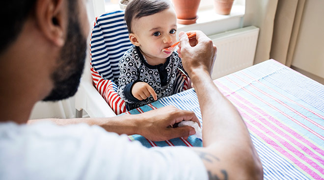 dad feeding his baby at the kitchen table