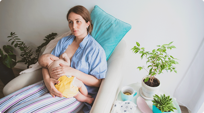 tired mom breastfeeding baby at home