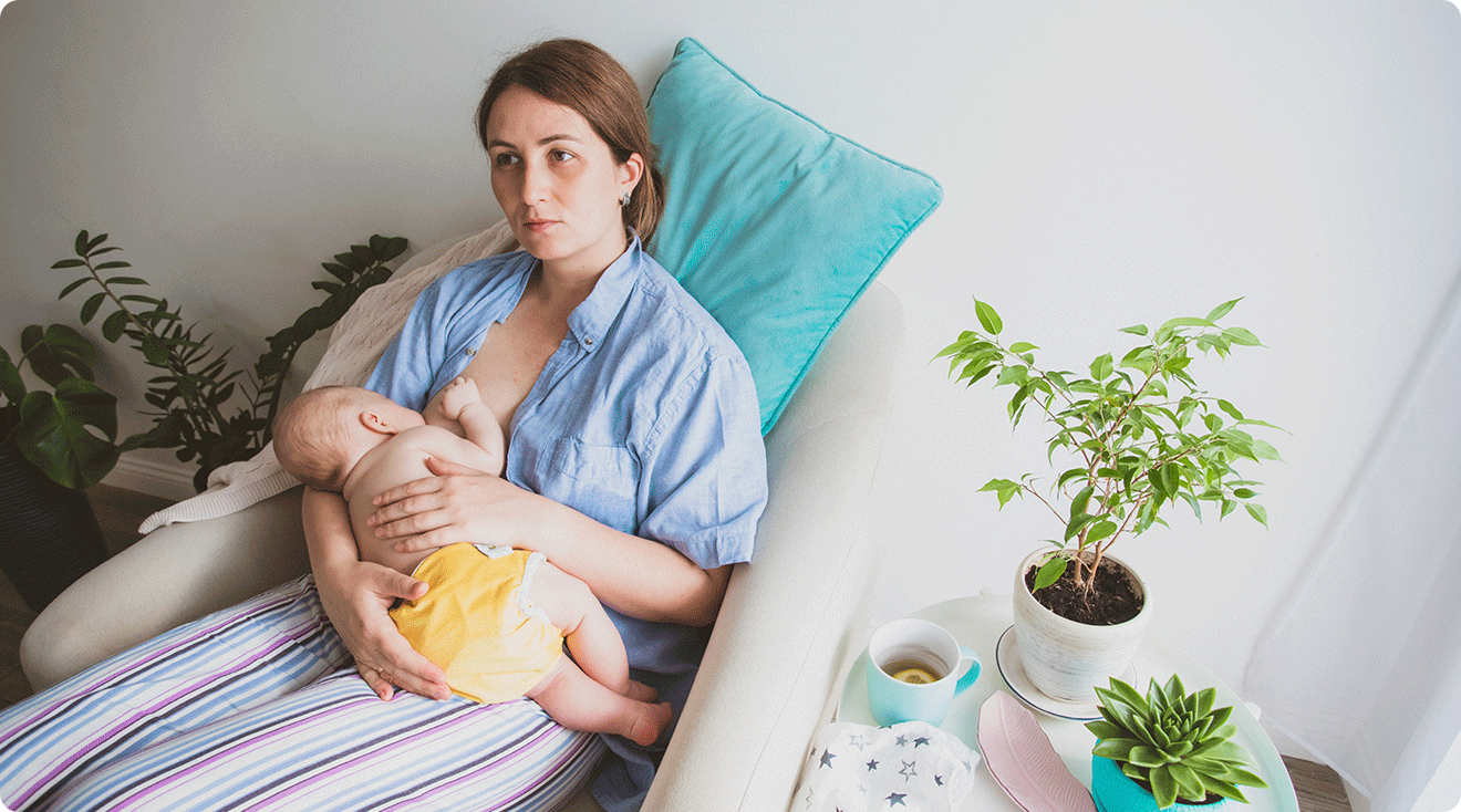 tired mom breastfeeding baby at home