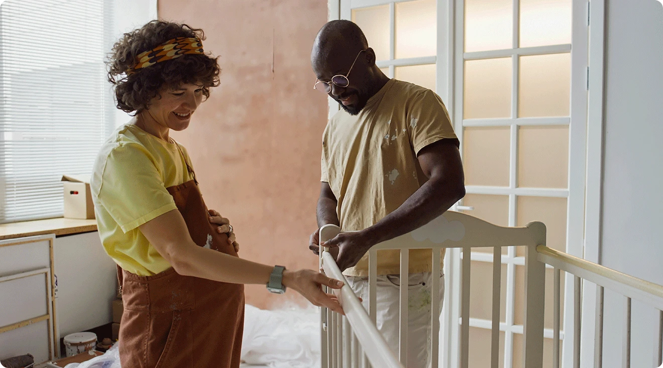 pregnant couple building a baby crib in nursery
