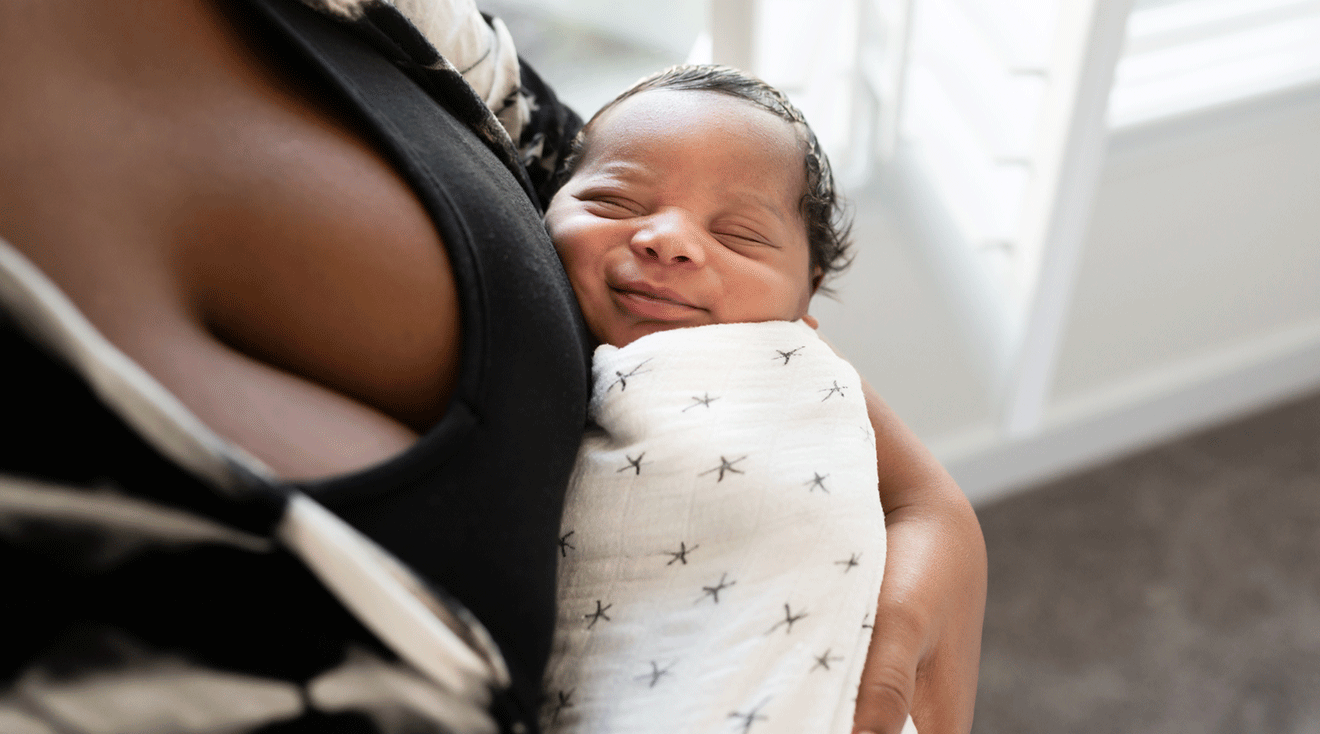 mother holding swaddled baby