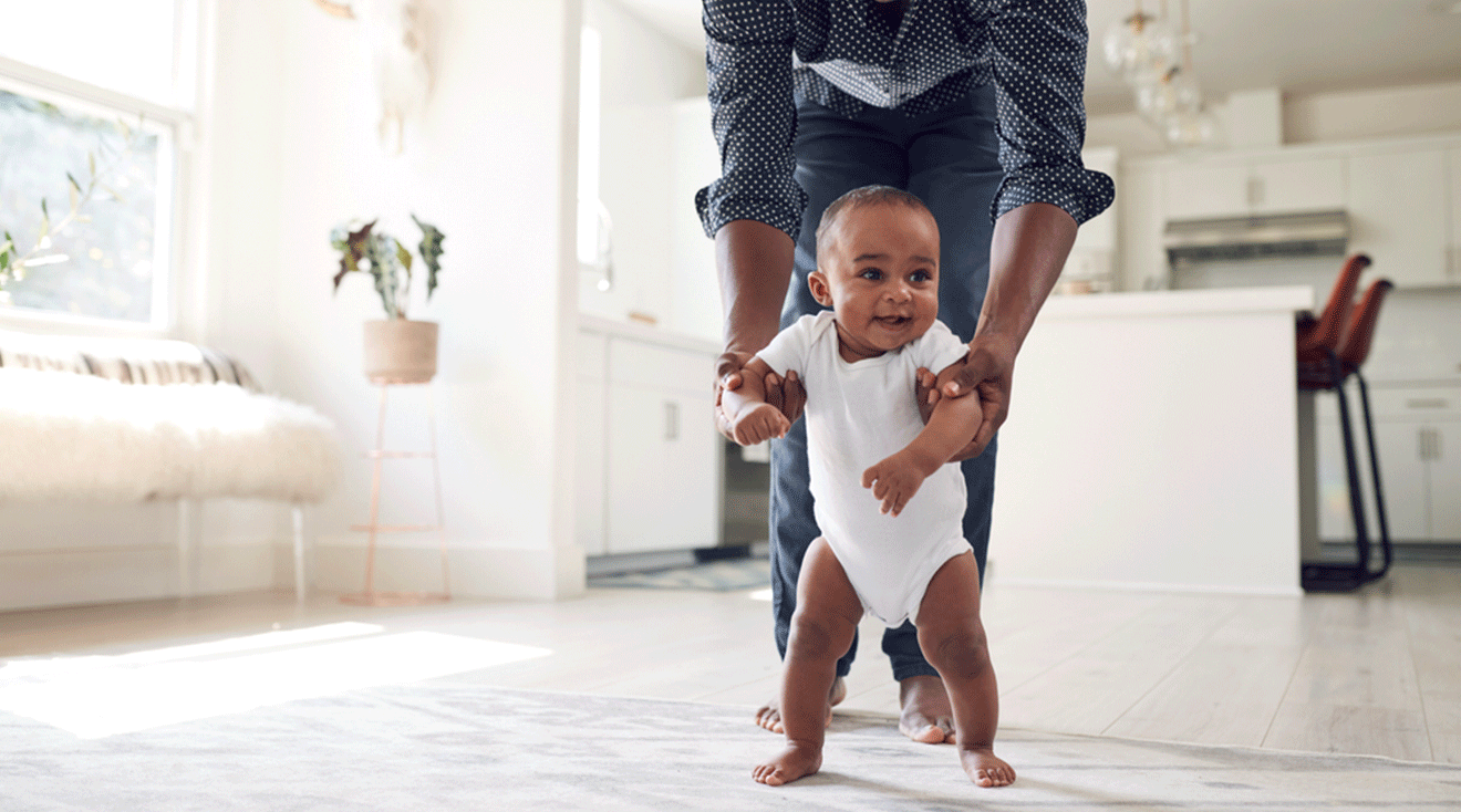 dad helping baby walk at home