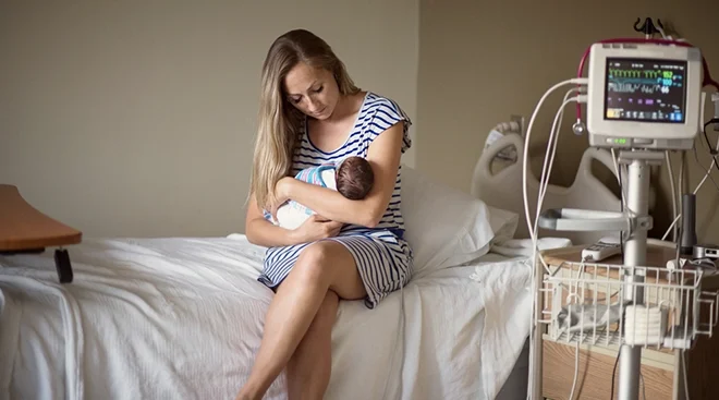 mother holding premature baby in hospital room