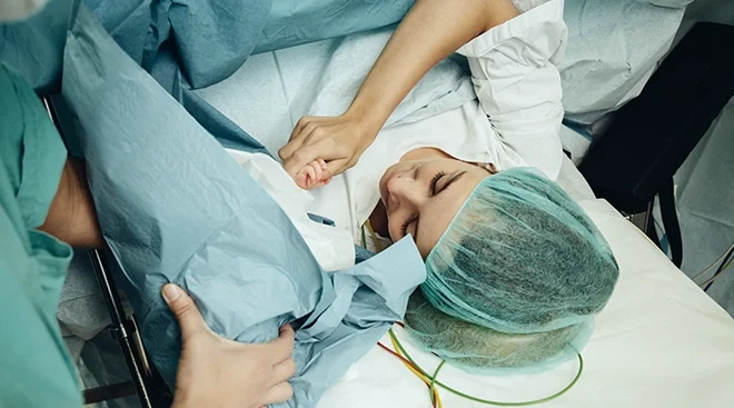 woman holding her baby's hand after undergoing c section procedure