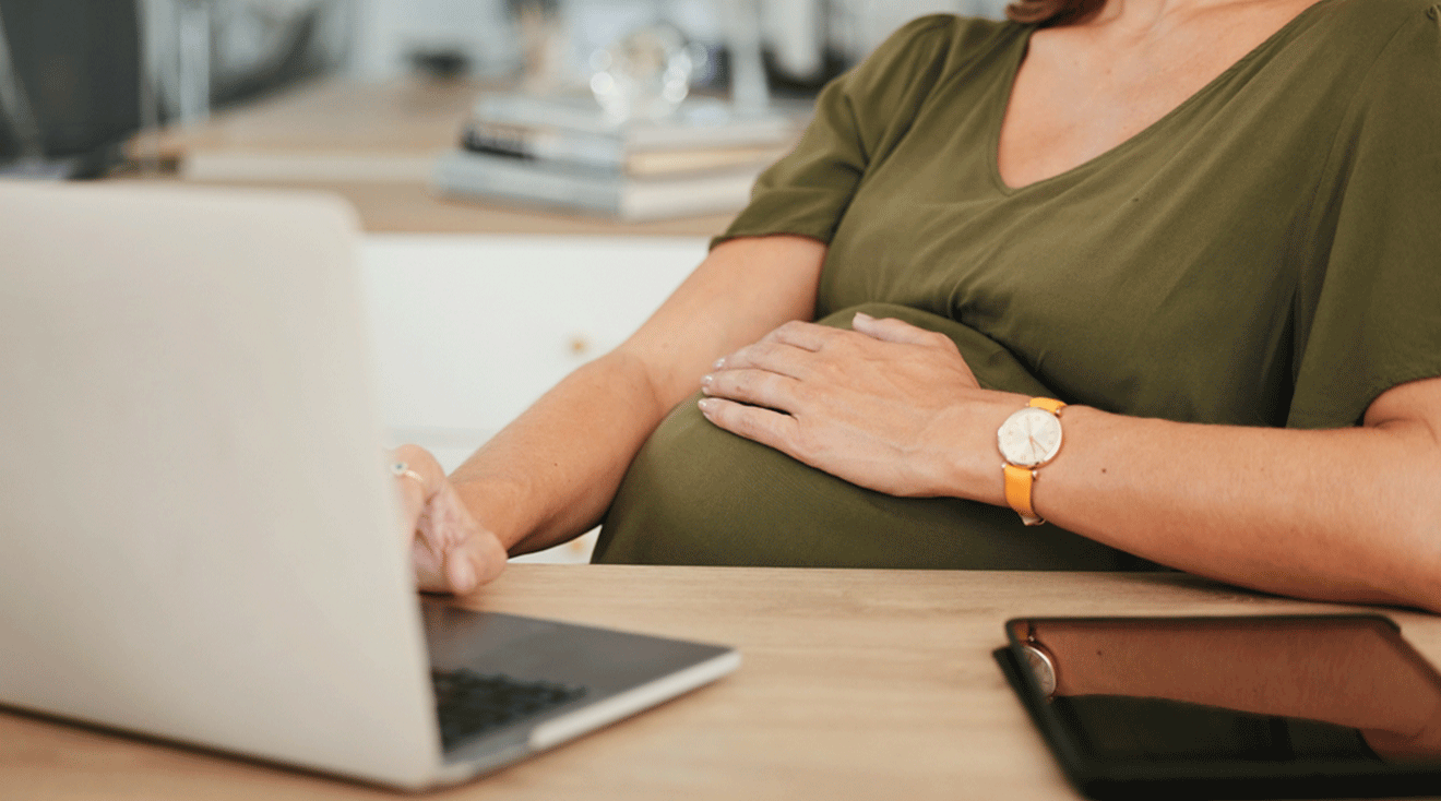 pregnant woman working on laptop at work desk