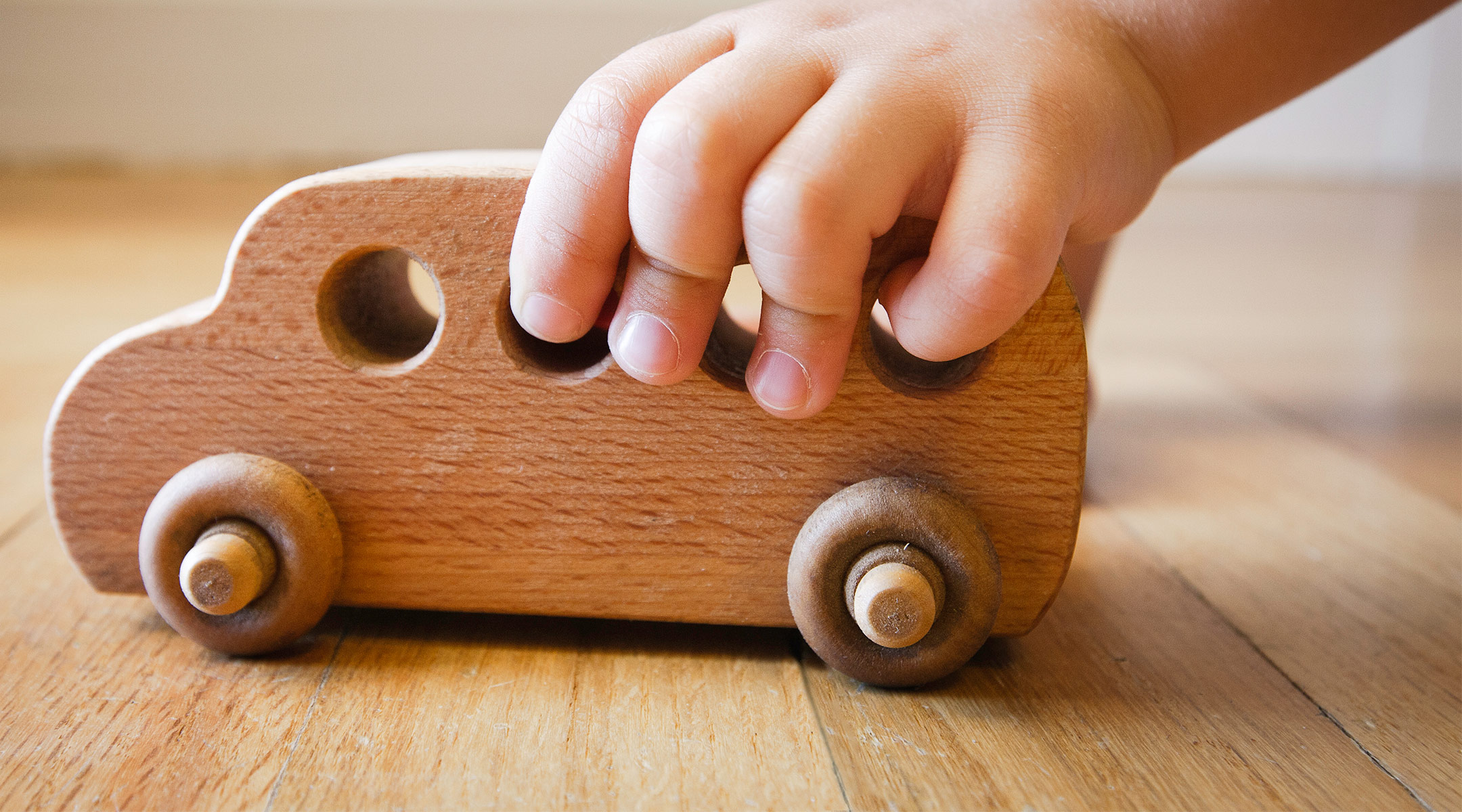 toddler hand playing with wooden toy car