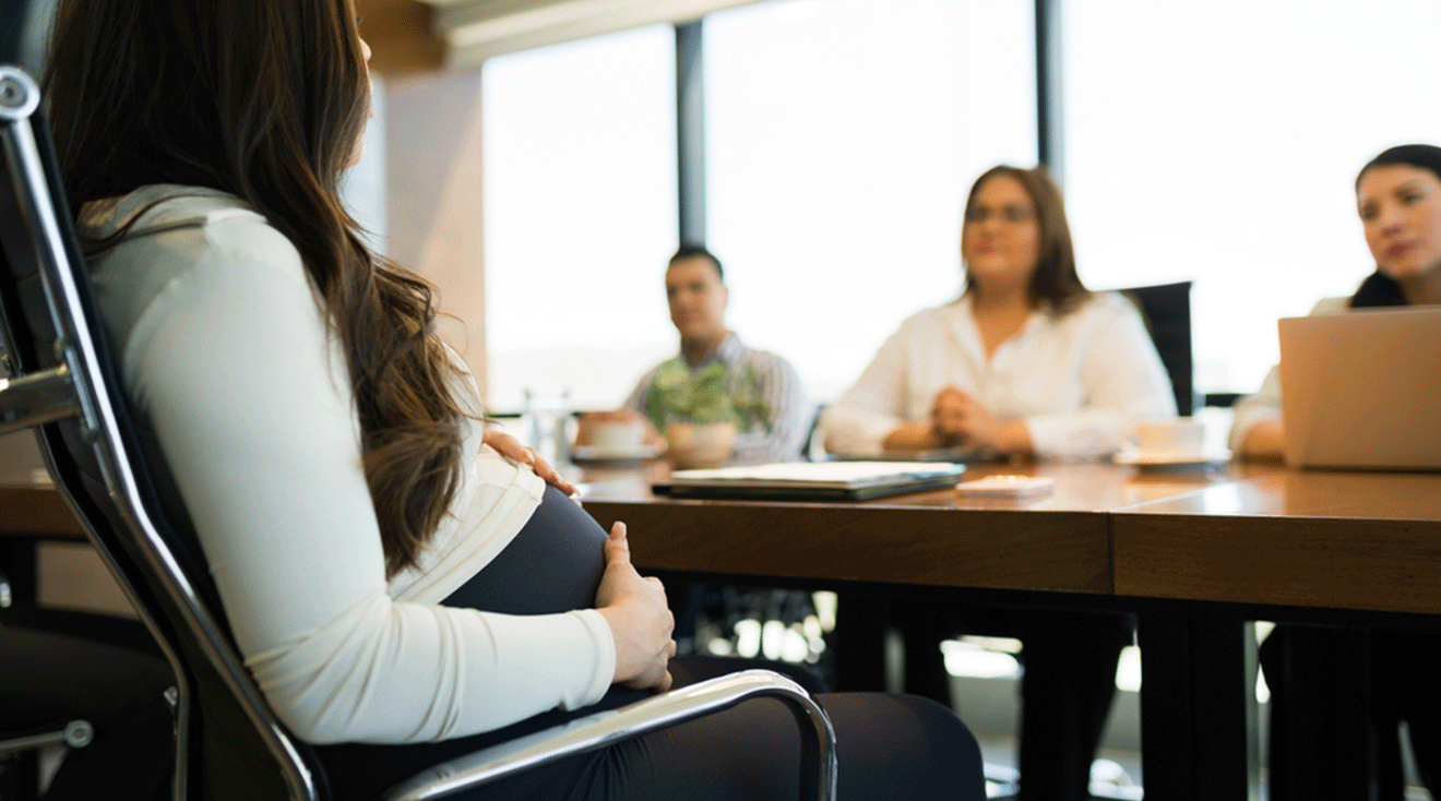 pregnant employee sitting at table with coworkers in officve