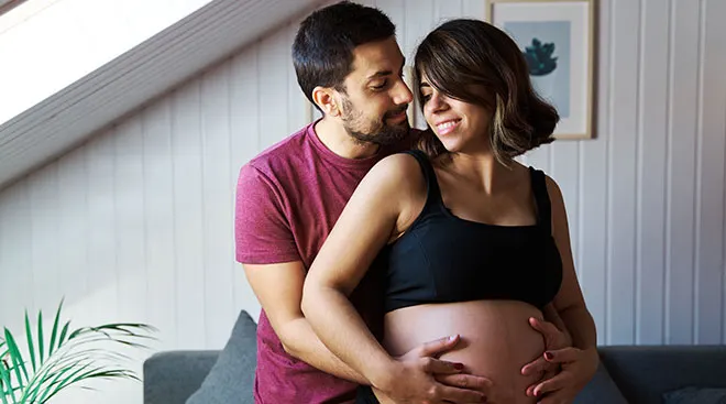 young pregnant couple hugging at home
