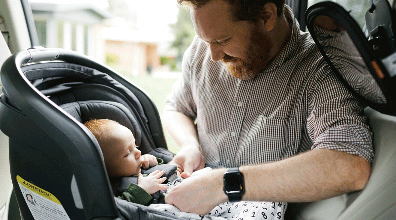 dad buckling in baby to car seat