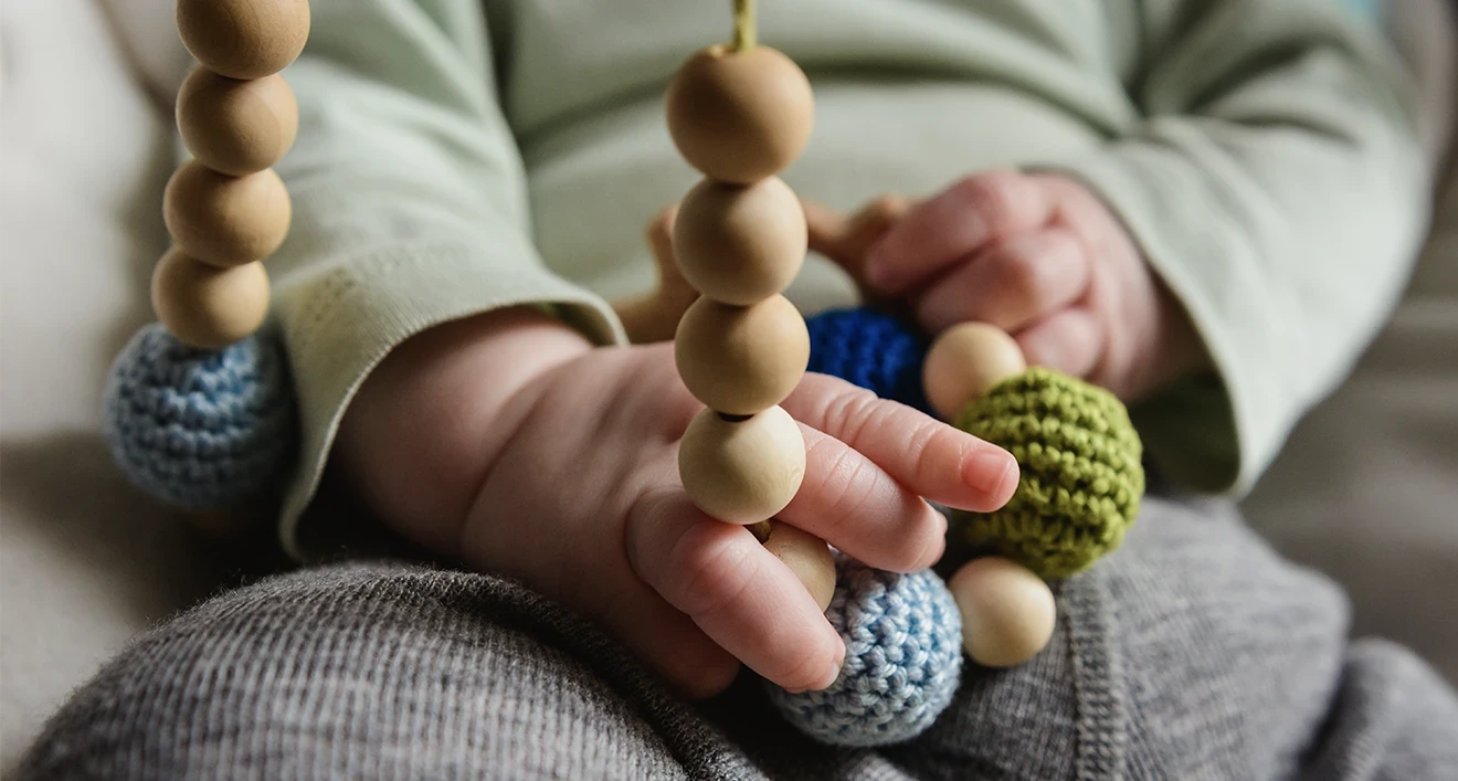 Teething necklaces held by baby-hero