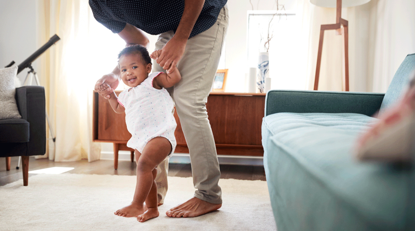 dad helping baby walk at home