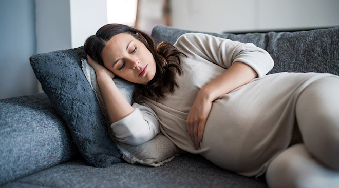 tired and sick pregnant woman on couch at home