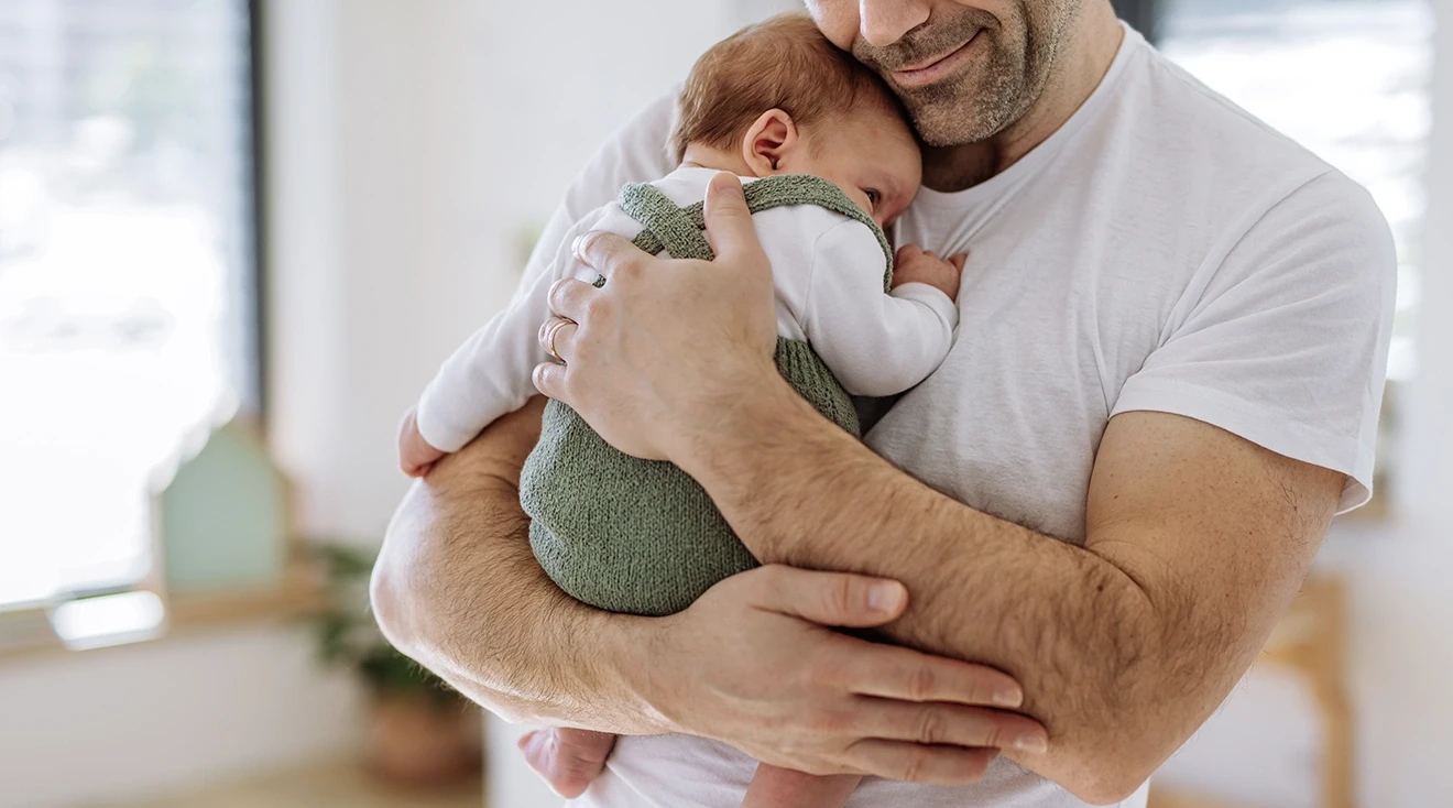 smiling father holding newborn baby at home