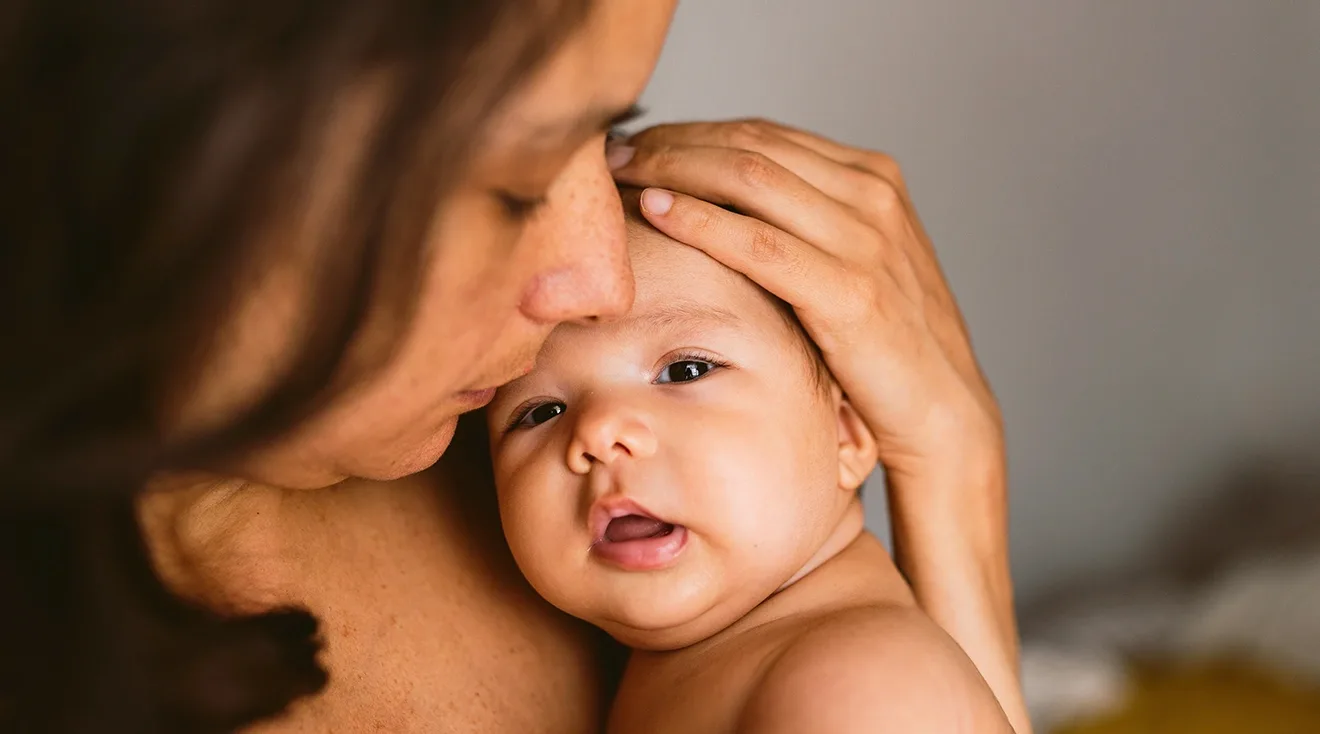 mother cuddling and kissing baby