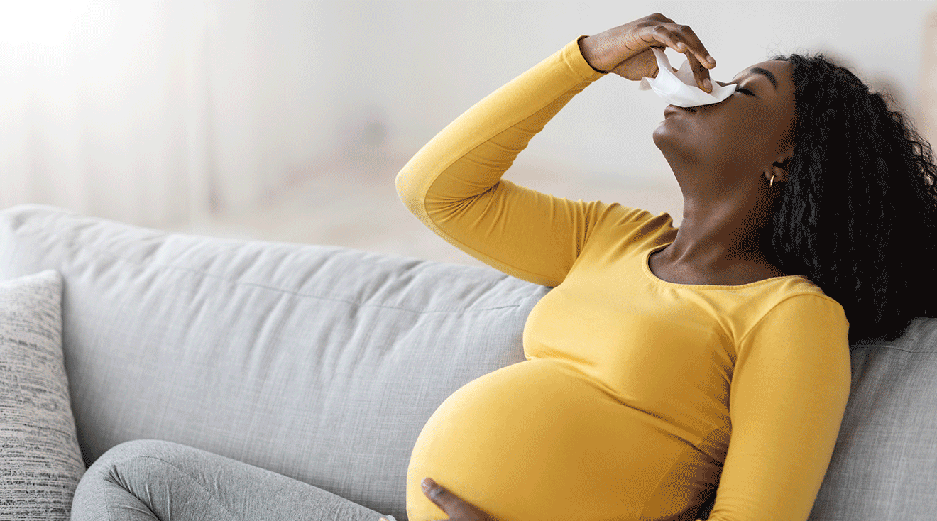 pregnant woman having a nosebleed while sitting on couch at home