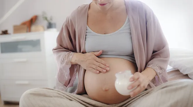 pregnant woman applying lotion to belly