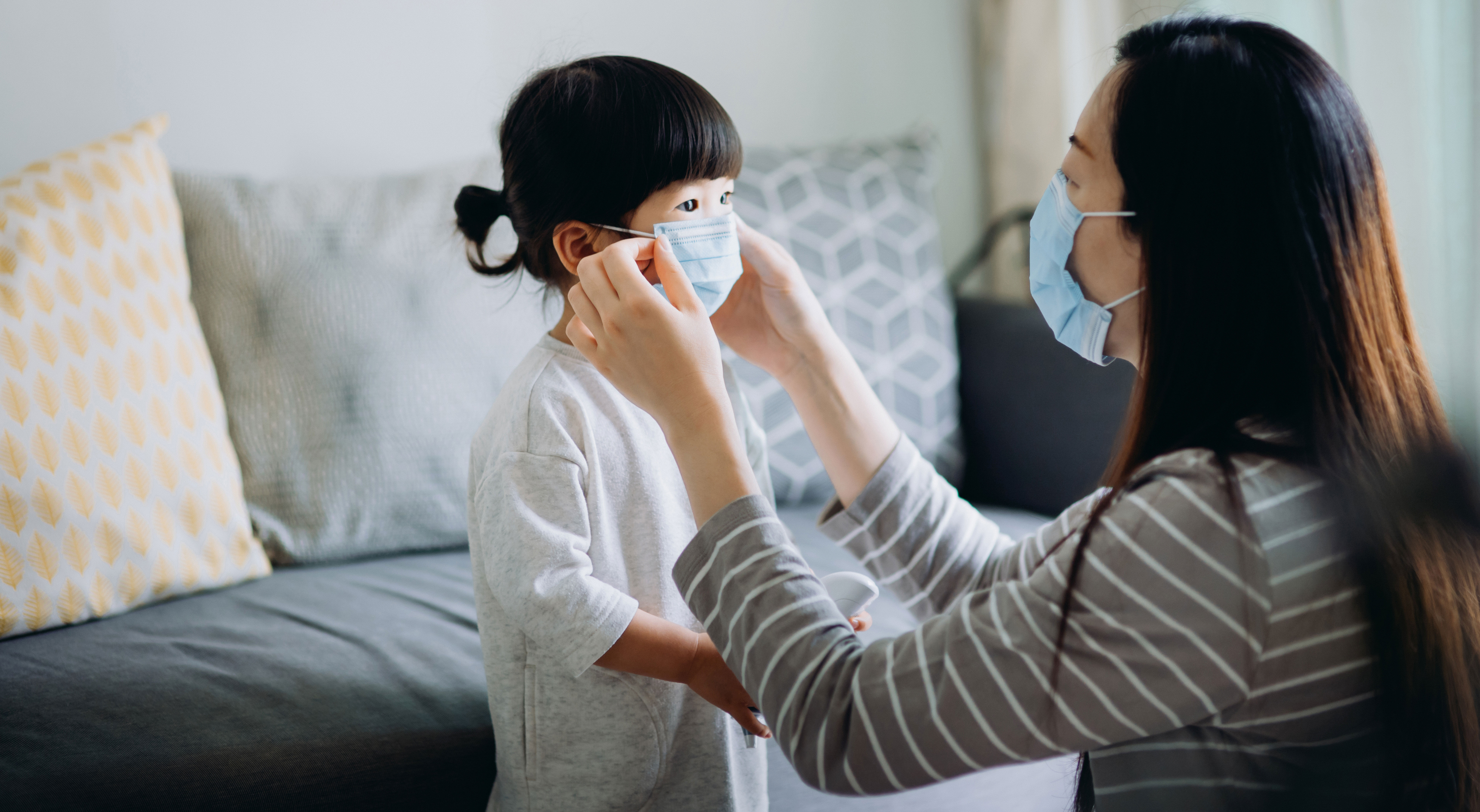 women helps child put on face mask before going outside