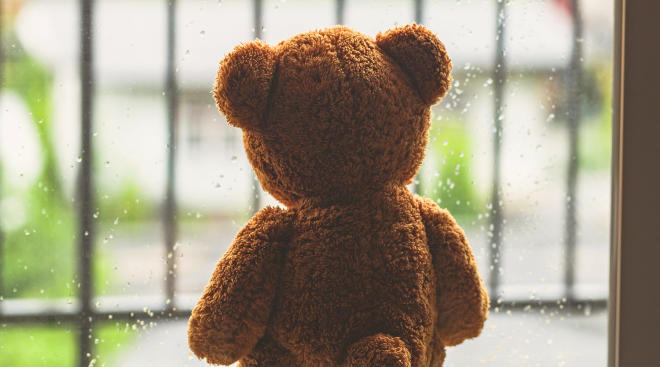 sad teddy bear looking out rainy window
