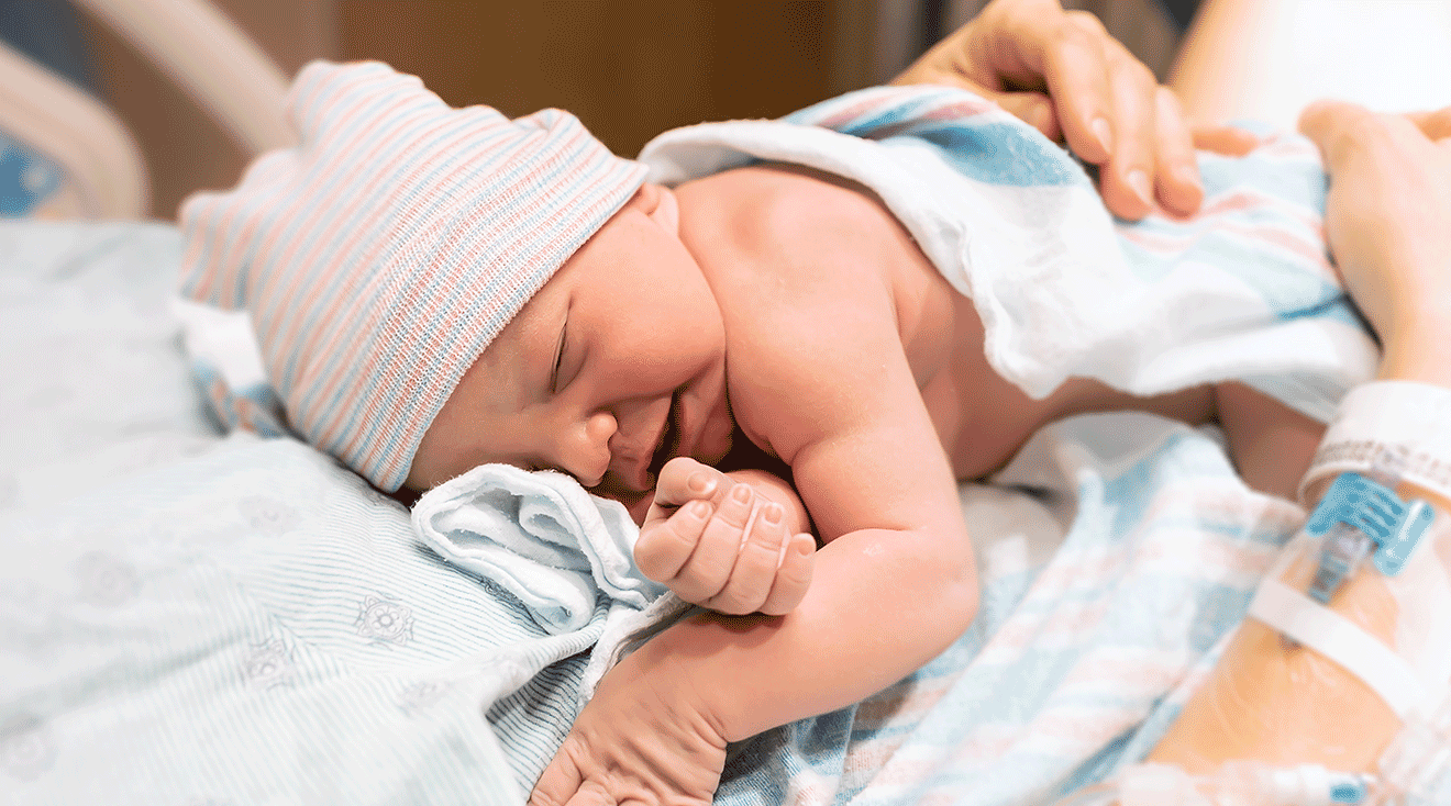 mom holding newborn baby in hospital after delivery