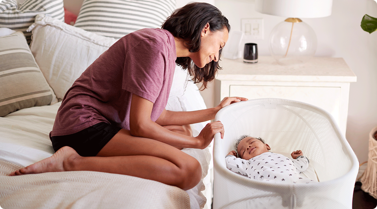 mom looking at baby in smart bassinet in bedroom