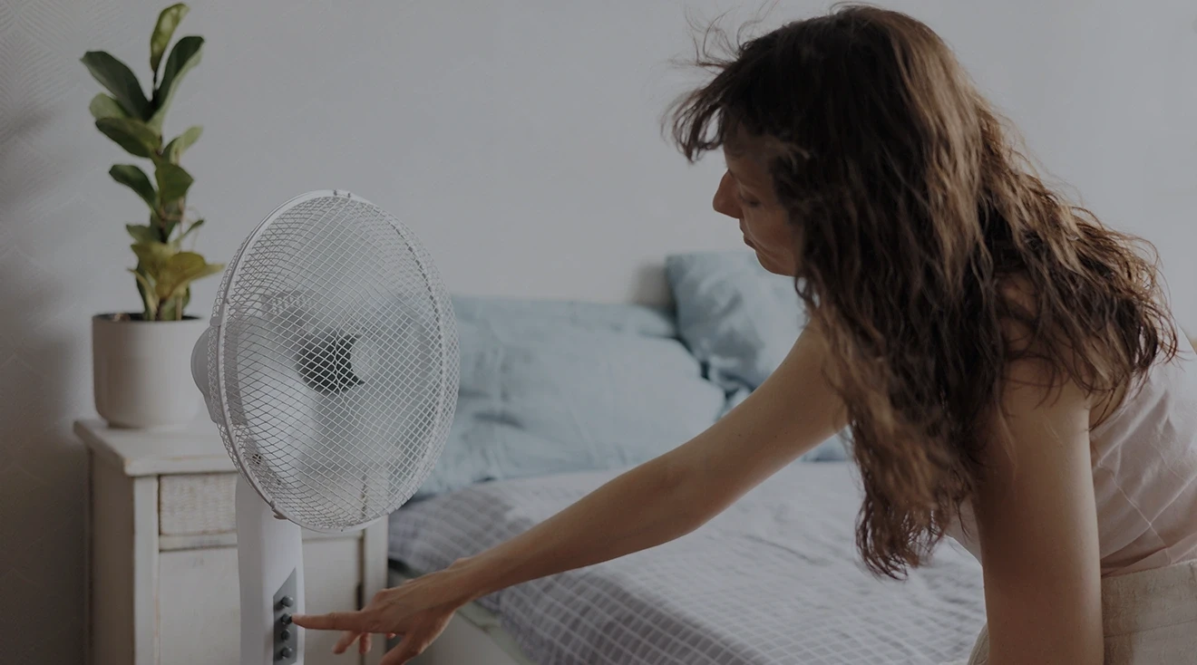 woman turning fan on in bedroom