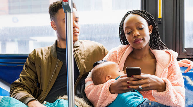 Mom breastfeeding her baby while riding a bus with her partner next to her. 