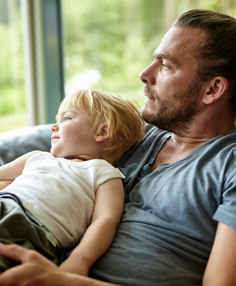 dad holding young son looks out of window