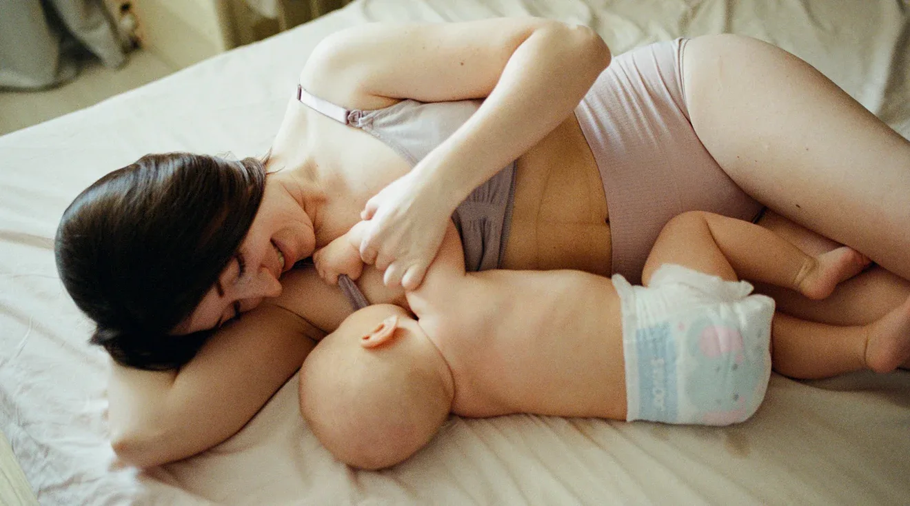 mother wearing a nursing bra while breastfeeding baby in bed