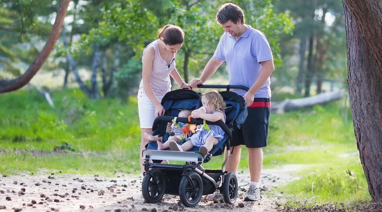 parents pushing double stroller with their 2 kids