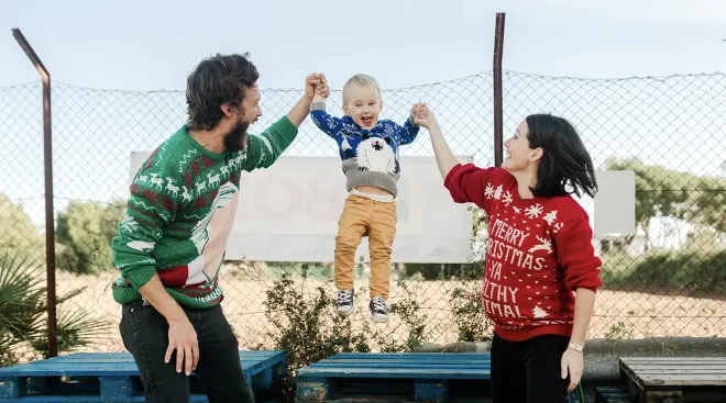 family wearing christmas sweaters and playing at christmas tree farm