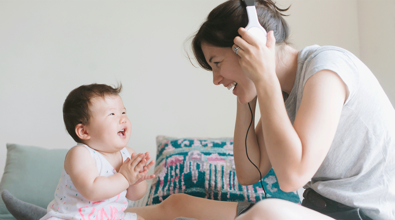 mom listening to podcast with headphones next to baby