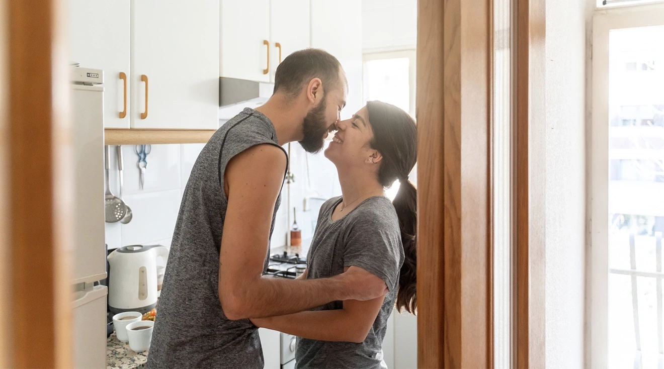 couple kissing in their kitchen at home