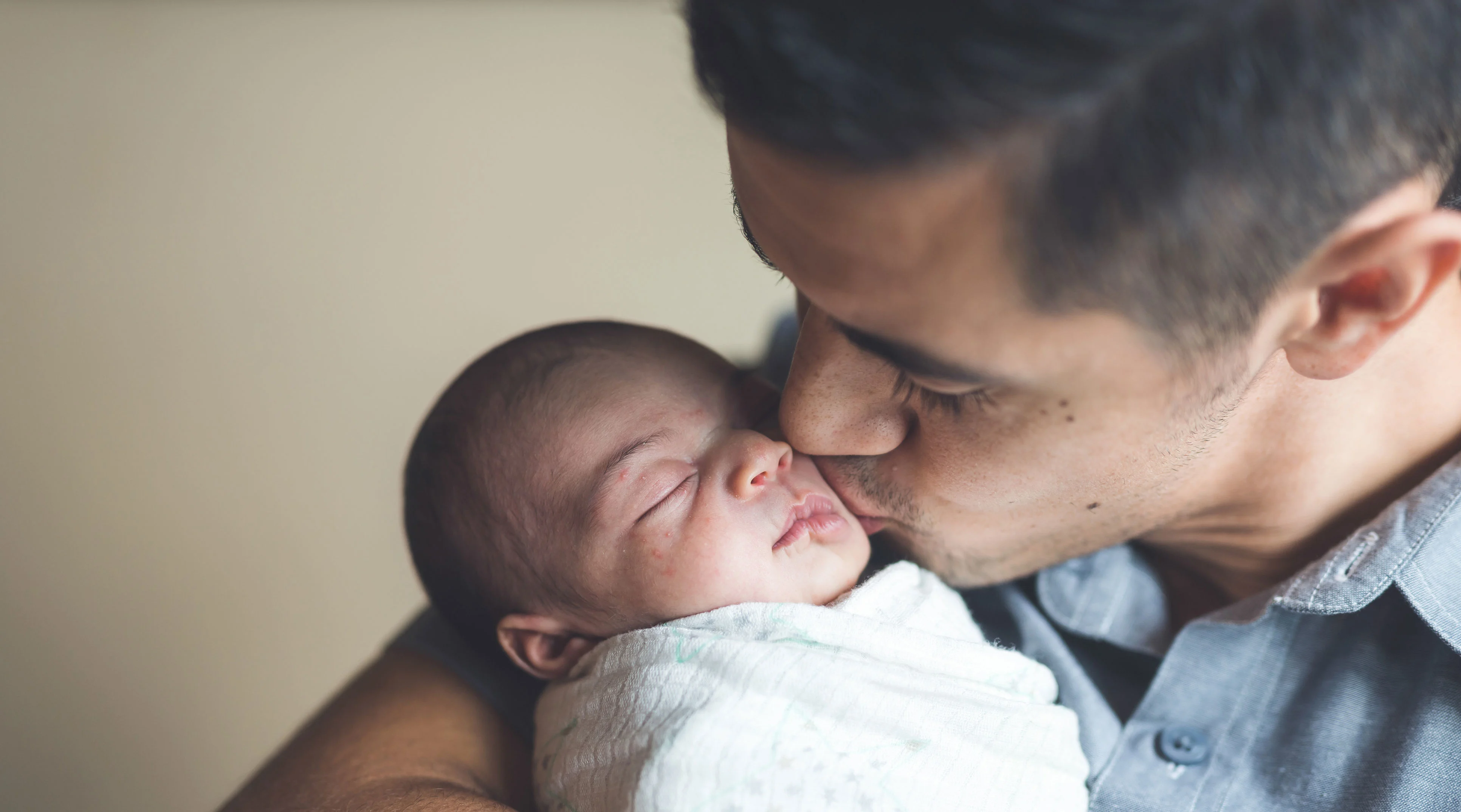 dad holds and kisses newborn baby