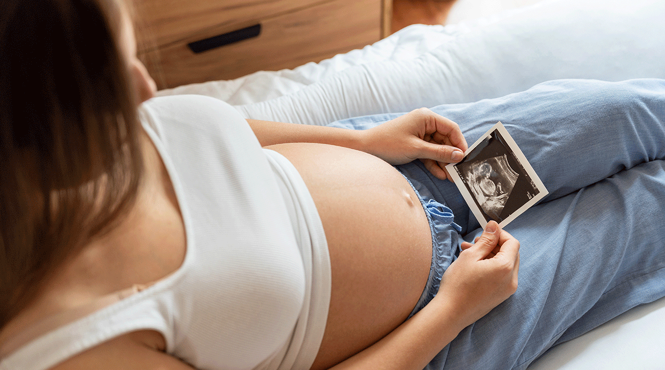 pregnant woman looking at ultrasound photo of baby in womb